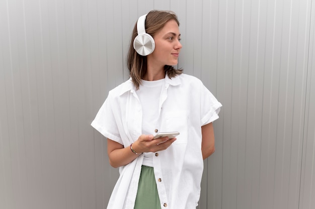 Бесплатное фото Женщина слушает музыку через наушники, держа в руке смартфон