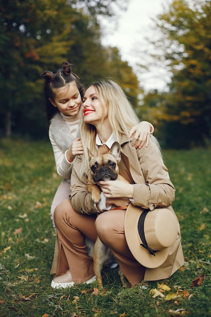 Woman, little girl and dog play and have fun in the autumn park