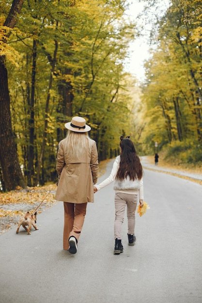 Free photo woman, little girl and dog walking in the autumn park