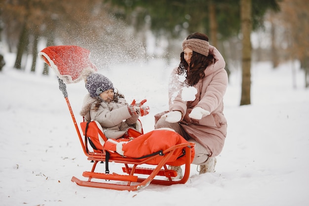 Woman and little girl in a park with sled