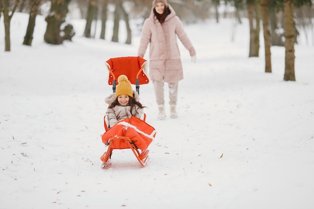 Donna e bambina in un parco con la slitta