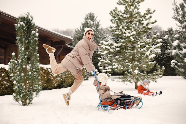 Free photo woman and little girl in a park with a sled