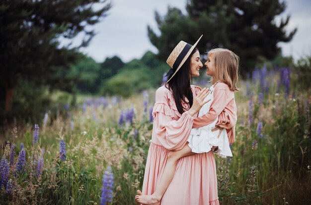 Woman and little girl in pink dresses pose on the field of lavander 