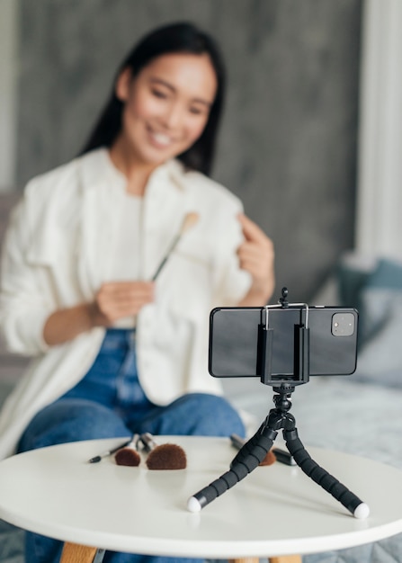 Woman live streaming about make up tools with her phone