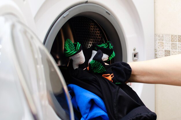 女性はスポーツウェアを洗う洗濯機をロードします