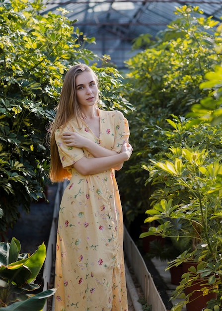woman in a long summer dress posing in a greenhouse