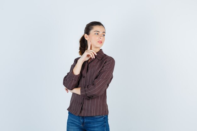 woman looking aside in brown striped shirt and looking focused. front view.