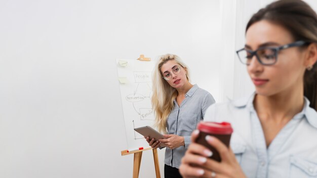 コーヒーを保持している同僚を見て女性