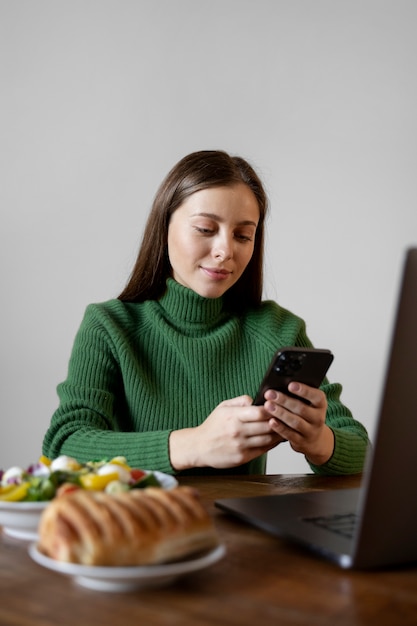 無料写真 食事をしながらスマートフォンを見ている女性