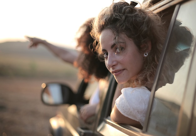 Woman looking back out of the car window behind another one pointing her finger