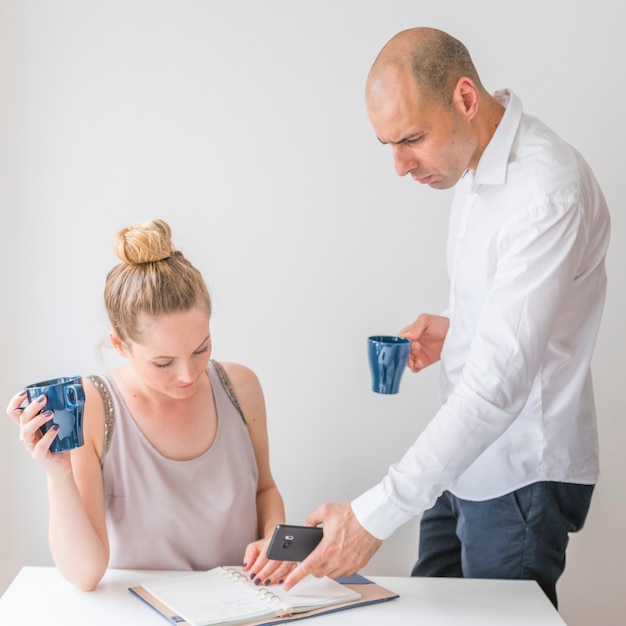 Woman looking at businessman holding calculator pointing at diary