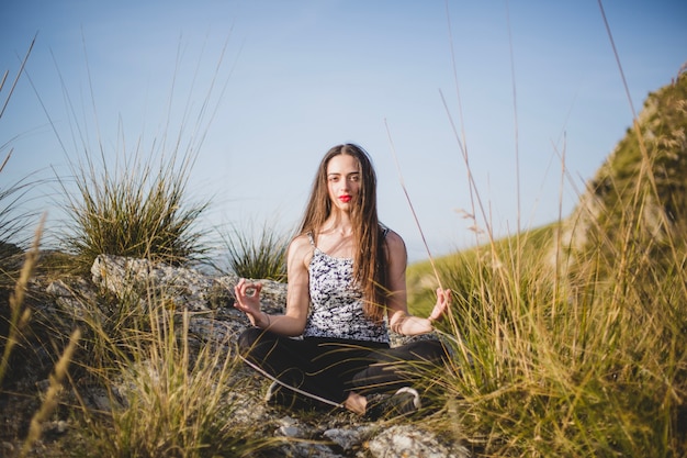 Woman looking at camera sitting on rock