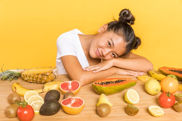Free photo woman looking at camera surrounded by fruits