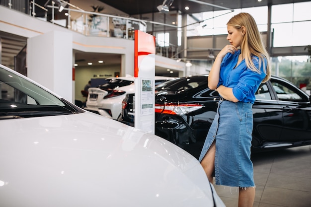 Foto gratuita donna che esamina un'automobile in una sala d'esposizione dell'automobile