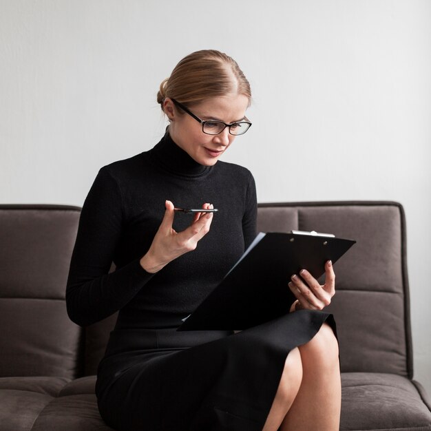 Woman looking at clipboard and holding mobile