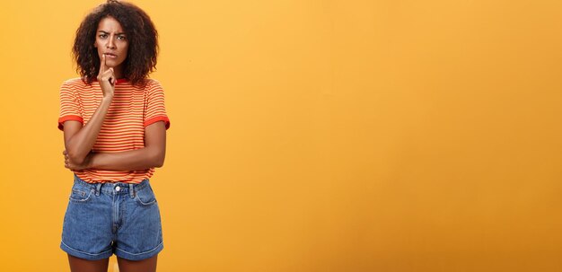 Woman looking concerned picking new furniture in store thoughtful focused and troubled smart african