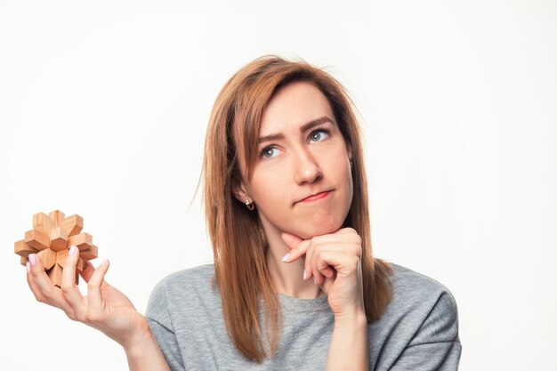 woman looking confused with wooden puzzle.