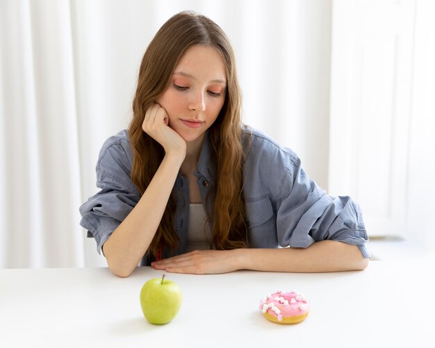 Woman looking at doughnut and apple