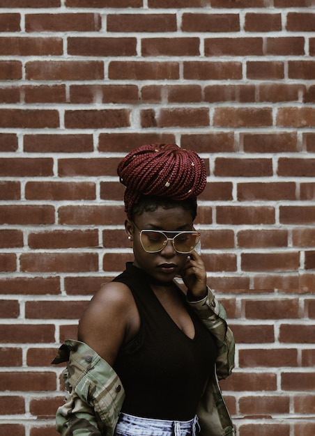 Free photo woman looking downwards in front of brick wall