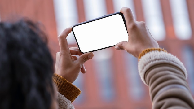 外の空の画面のスマートフォンを見ている女性