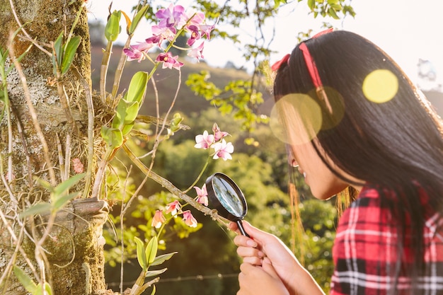 拡大鏡で花を見る女性