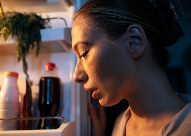 Foto gratuita donna che guarda nella vista laterale del frigorifero