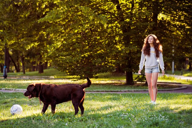 Donna che esamina il suo cane che gioca con la palla nel parco