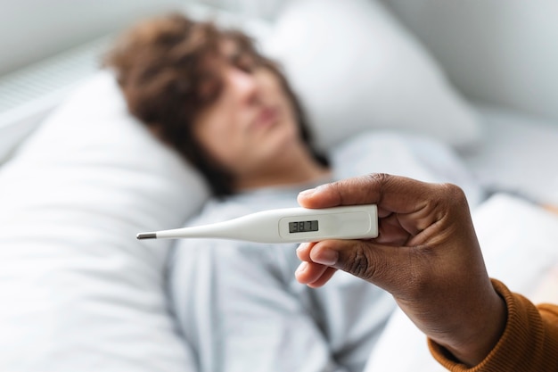 Free photo woman looking at her friend's temperature on a thermometer