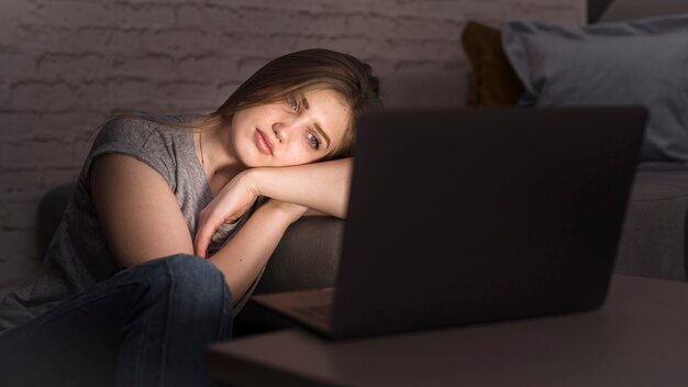 woman looking at her laptop with head on arm