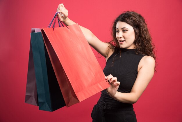 Woman looking at her new buying clothes on red background