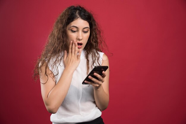 Woman looking on her phone on red