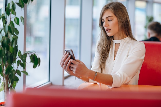 女性はコーヒーショップに座って彼女の電話を見て