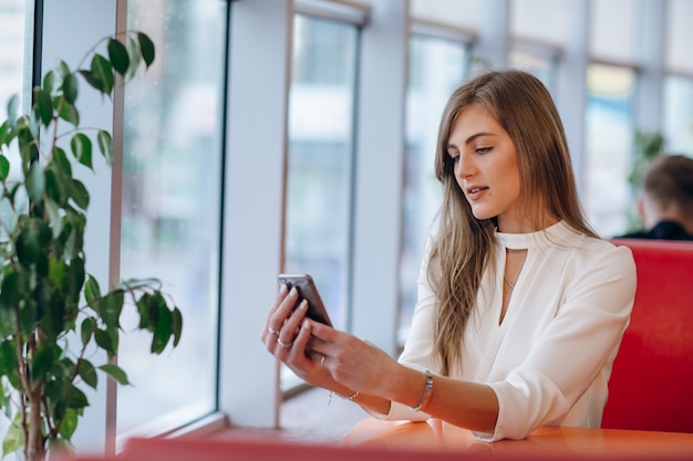 Woman looking at her phone sitting in a coffee shop