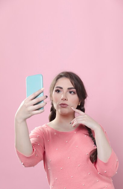 woman looking at her phone and taking selfie