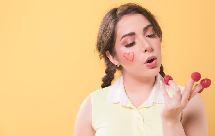 Free Photo woman looking at her raspberries covered fingers