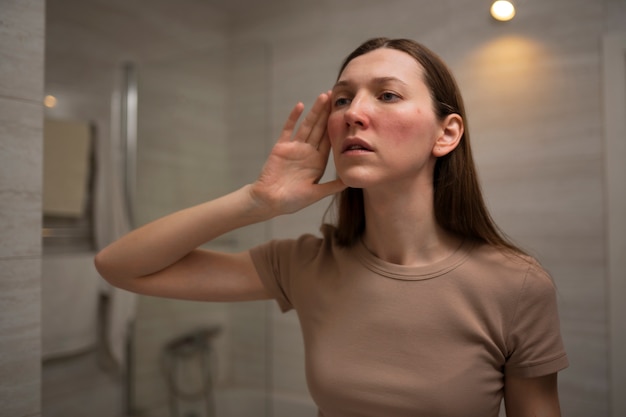 Free photo woman looking at her rosacea in the mirror