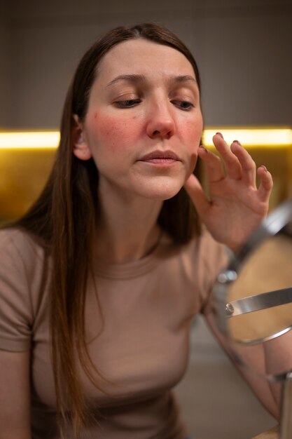 Free photo woman looking at her rosacea in the mirror