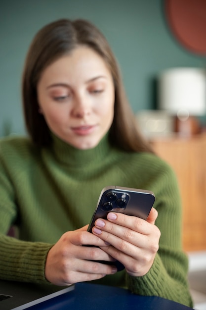 Free photo woman looking at her smartphone while being at home