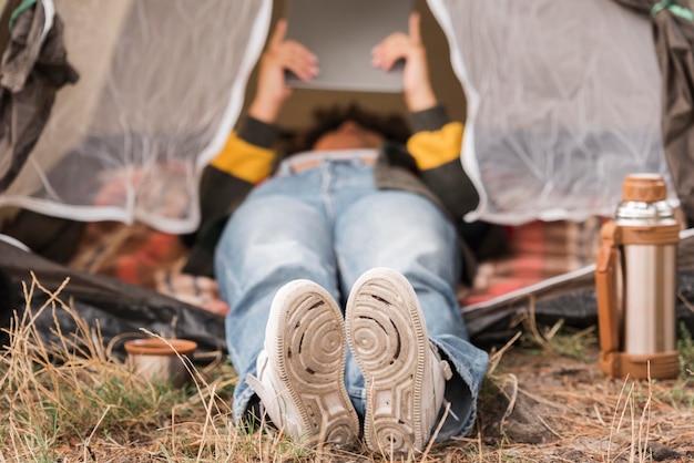 Free photo woman looking at her tablet in her tent while camping