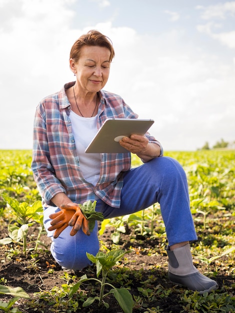 Woman looking at her tablet while holding some carrots