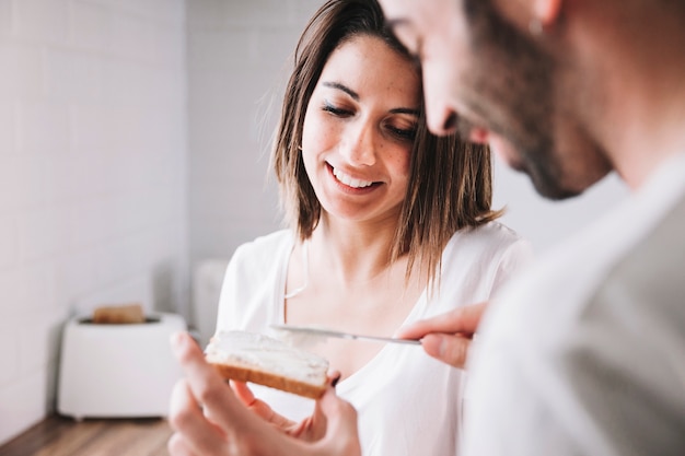 Woman looking at man making toast