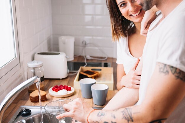 Woman looking at man washing dishes