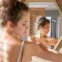 Free photo woman looking in mirror and applying cream on hands