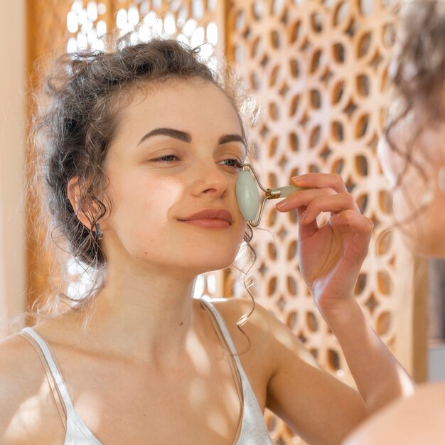 Woman looking in mirror and doing face massage