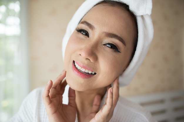 woman looking at mirror at home and checking her face