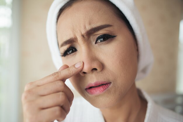 woman looking at mirror at home and checking her face