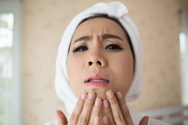 woman looking at mirror at home and checking her face