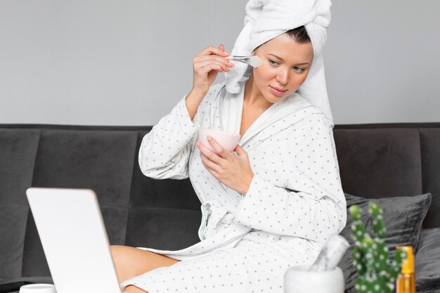 Woman looking in the mirror while applying beauty products