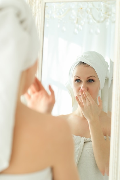 シャワーの後彼女の頭にタオルで鏡を探している女性