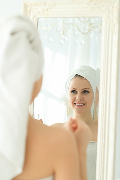 シャワーの後彼女の頭にタオルで鏡を探している女性